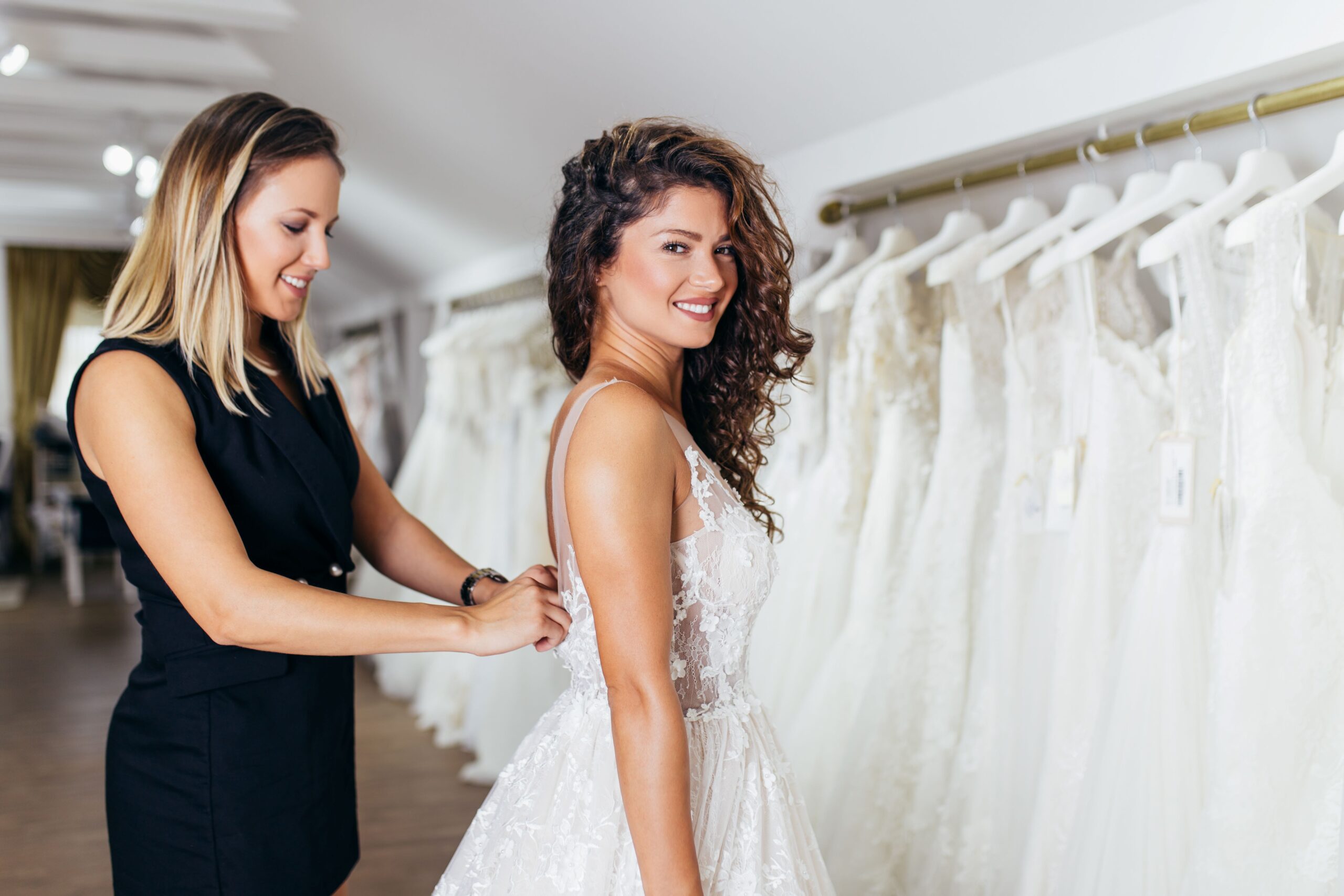 Schöne junge brünette Frau wählt Hochzeitskleid in einem Brautsalon.