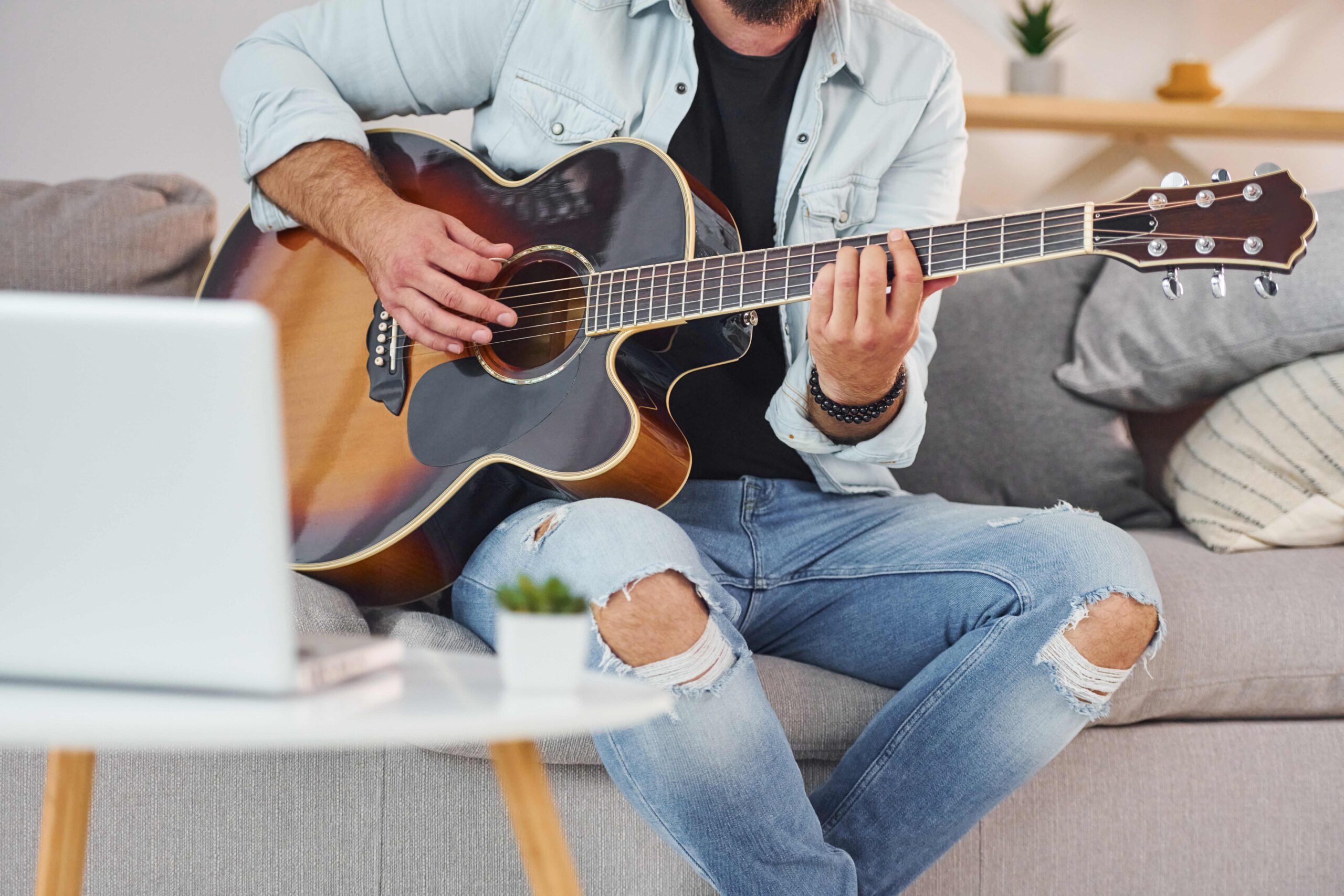 Prozess des Songwritings. Mann in Freizeitkleidung und mit Akustikgitarre ist drinnen