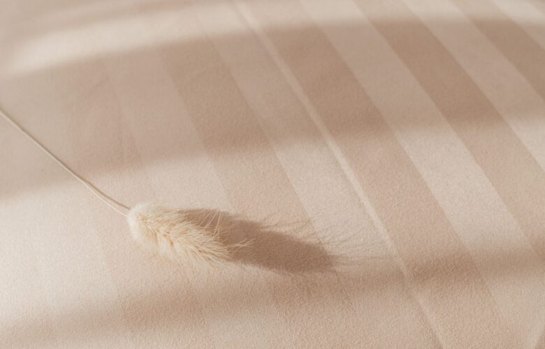 Detailaufnahme von Bettwaesche Baumwolle in Beige mit zarter Streifenstruktur und natuerlichem Licht