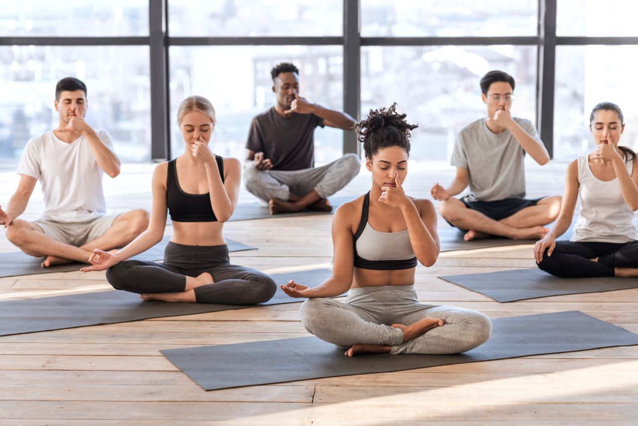 Gruppe von Menschen sitzt auf Yogamatten und uebt wechselseitiges Atmen, Darstellung von gemeinsamer Praxis und Was ist Breathwork