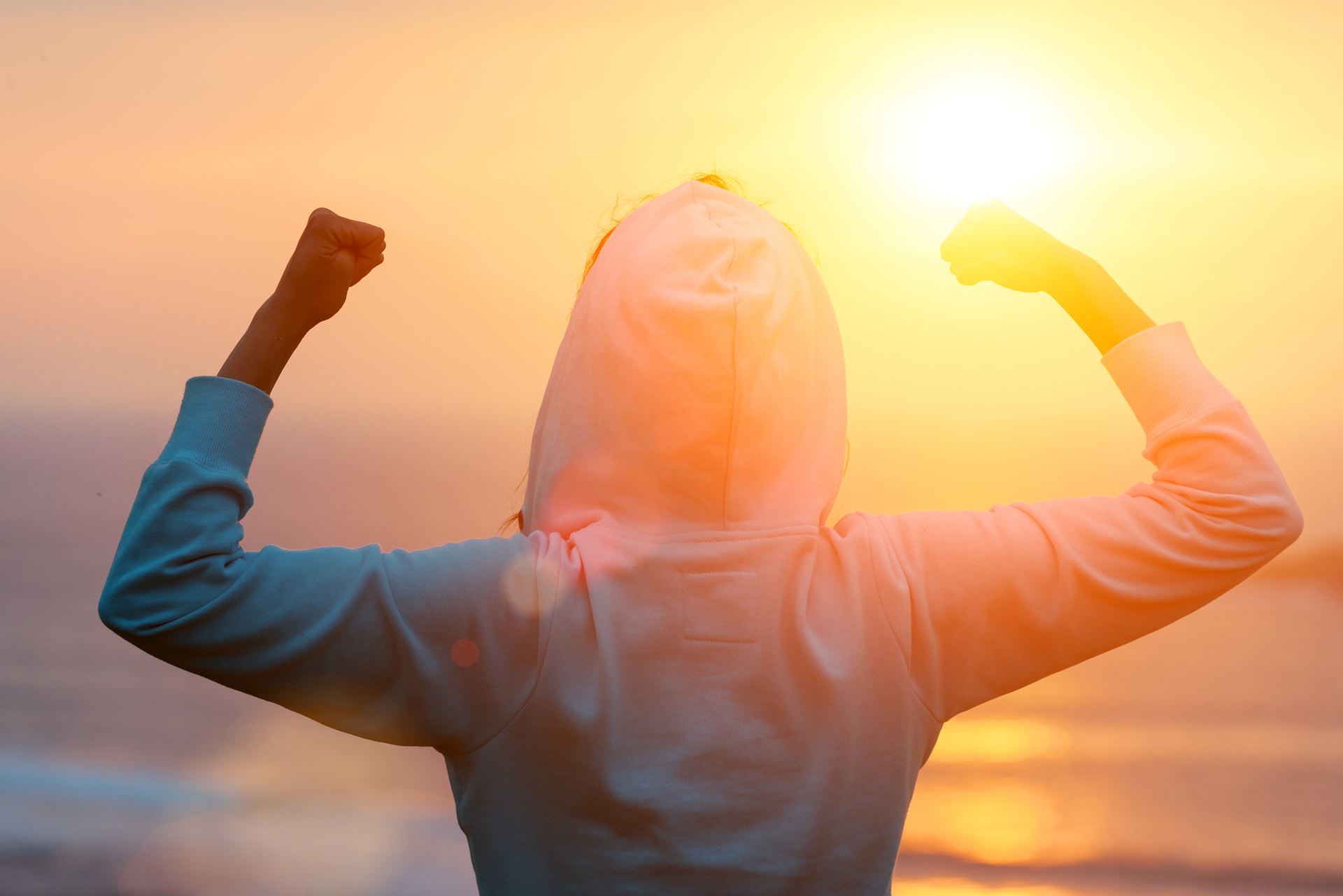 Motivierte Person mit erhobenen Armen bei Sonnenaufgang | Radiologie Frankfurt