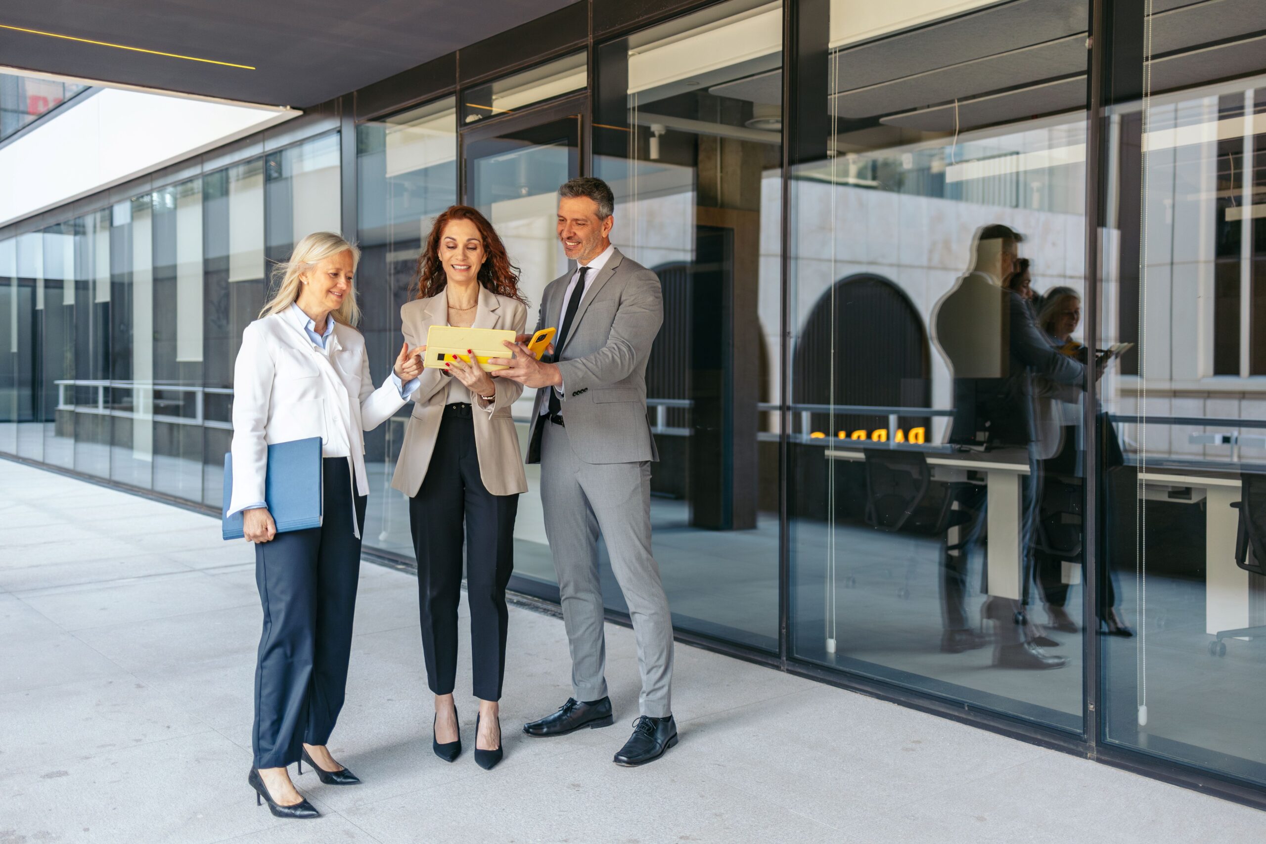 Raumsysteme im modernen Bürokomplex: Mitarbeitende besprechen Planungsunterlagen vor einer Glasfassade